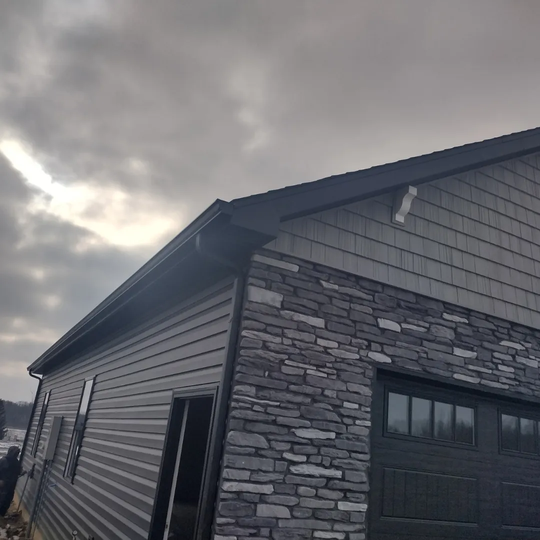 Gutters installed on dark stone and siding home
